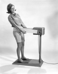 Lady standing on machine with vibrating belt around her hips